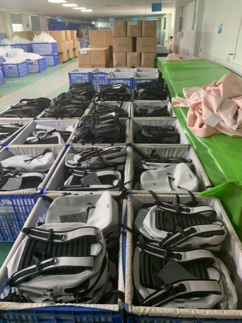 White welded backpack bodies with black strap assemblies staged in lined bins